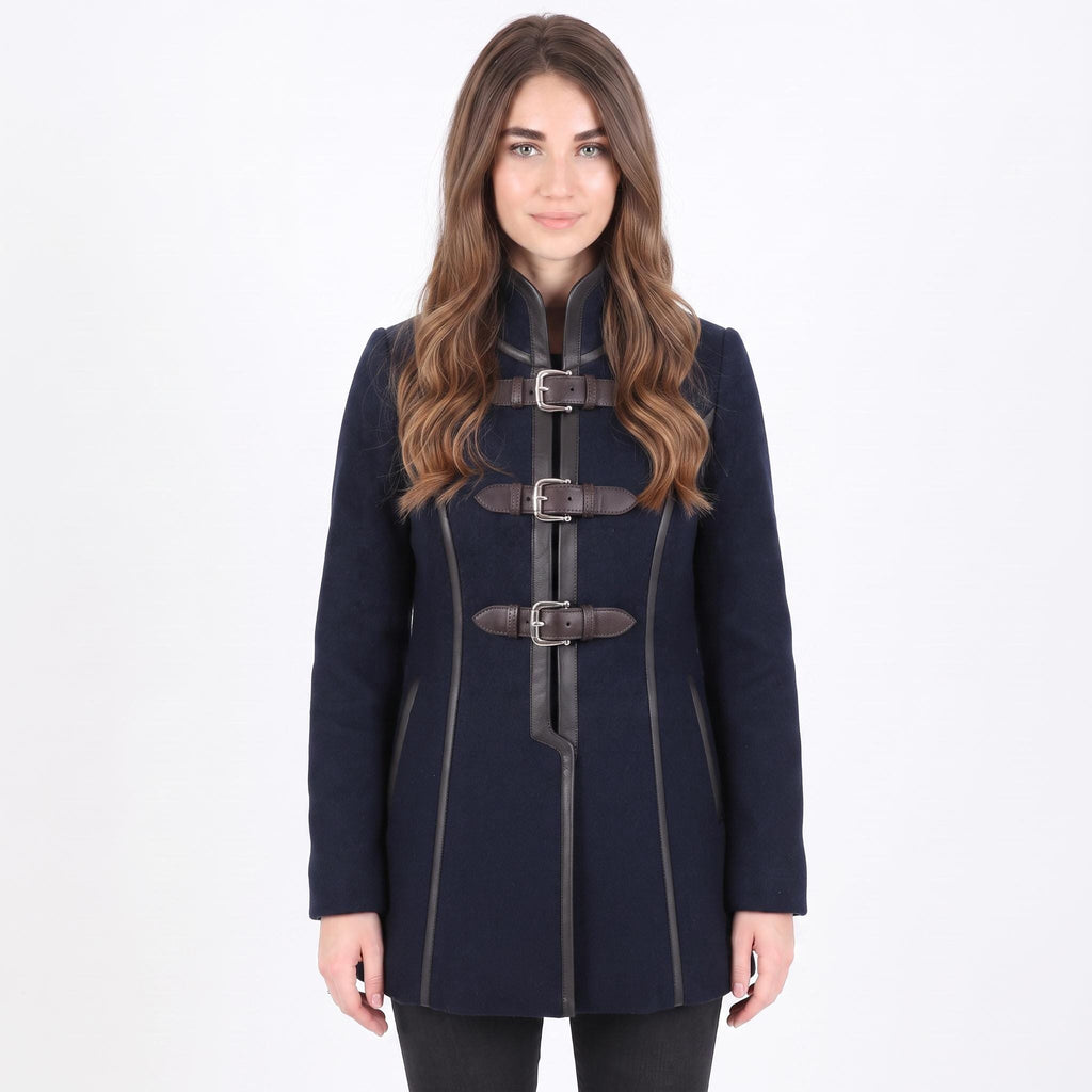 A woman modeling a dark navy blue coat with brown leather-like doggle straps and silver buckles, set against a plain white studio background.